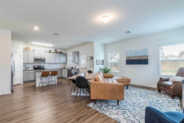 living area with visible vents, baseboards, and wood finished floors