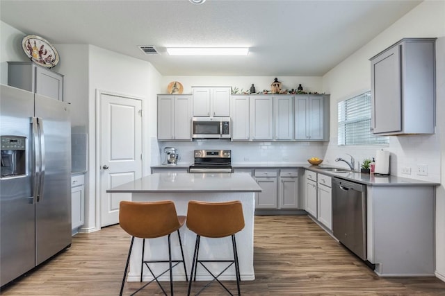 kitchen featuring stainless steel appliances, a kitchen island, gray cabinets, and visible vents