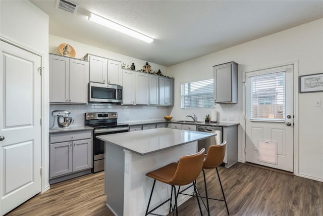 kitchen with appliances with stainless steel finishes, visible vents, a sink, and gray cabinetry