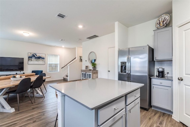 kitchen with visible vents, open floor plan, gray cabinets, stainless steel refrigerator with ice dispenser, and backsplash