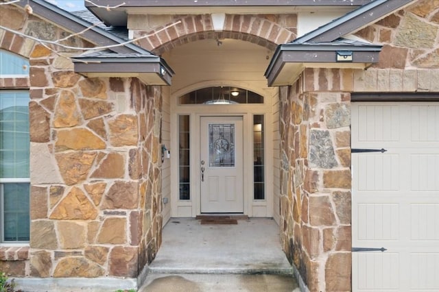 entrance to property featuring a garage and stone siding