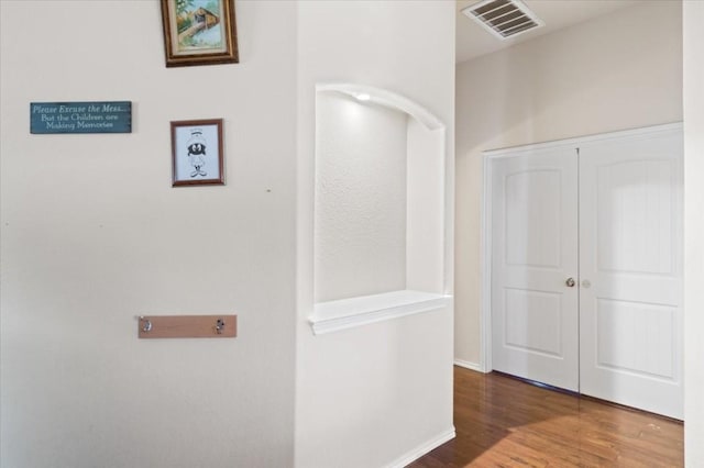 hallway with visible vents, baseboards, and wood finished floors