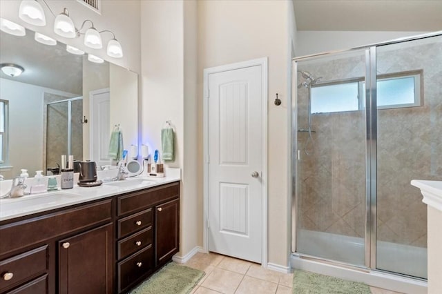 full bathroom featuring a stall shower, double vanity, a sink, and tile patterned floors