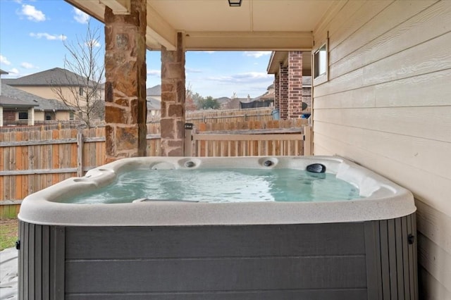 view of patio with a hot tub and fence