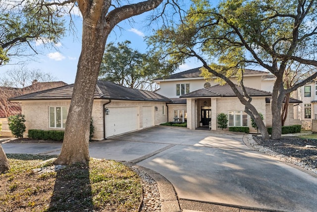 view of front of home featuring driveway, an attached garage, and brick siding