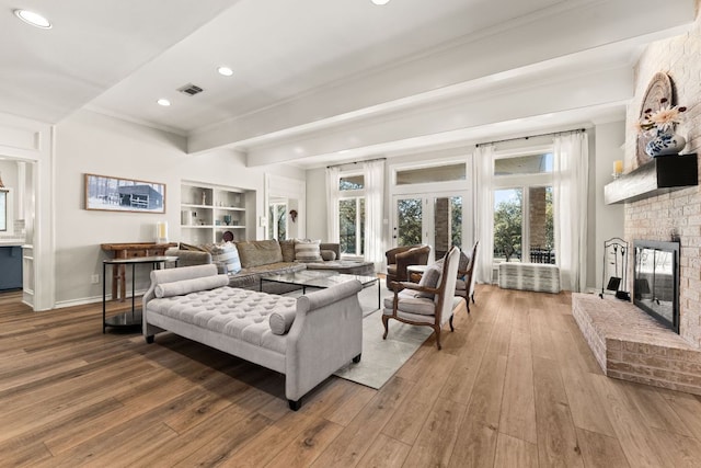 living area featuring baseboards, visible vents, a fireplace, and hardwood / wood-style floors