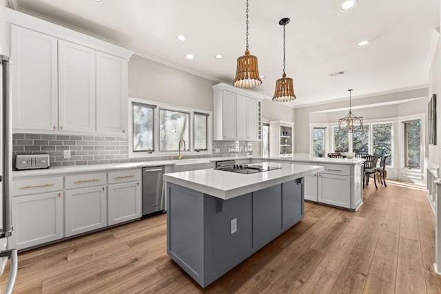 kitchen with black electric stovetop, a peninsula, light countertops, a center island, and dishwasher