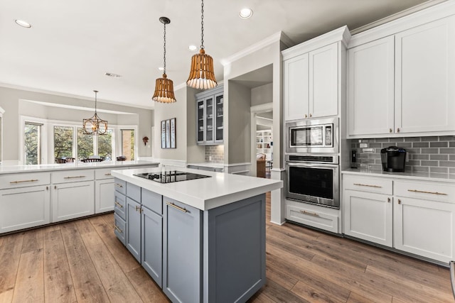 kitchen with ornamental molding, a center island, stainless steel appliances, light countertops, and backsplash