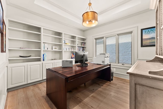 office space featuring ornamental molding, light wood-type flooring, and a raised ceiling