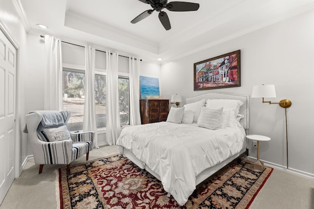 bedroom featuring baseboards, a raised ceiling, ceiling fan, carpet, and crown molding