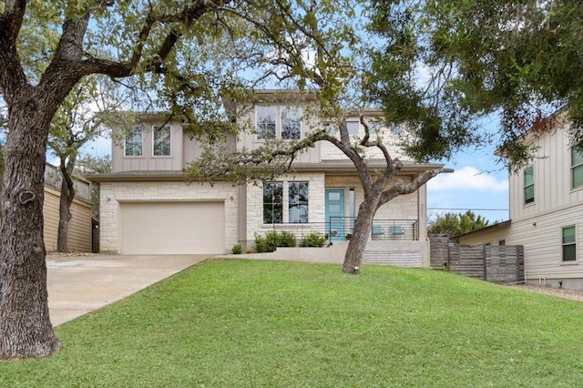 traditional home with a front yard, fence, driveway, an attached garage, and stone siding