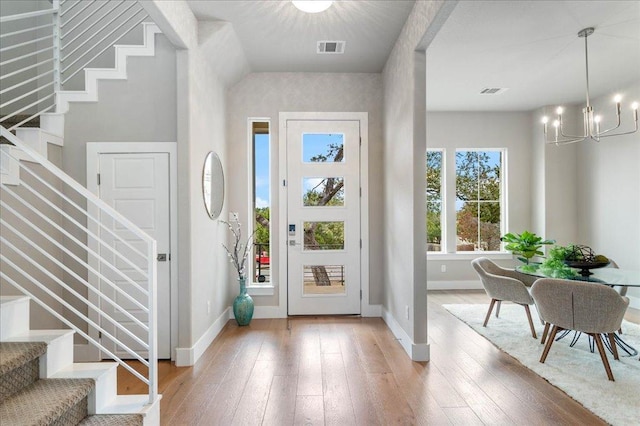 entryway with visible vents, baseboards, light wood-style floors, stairway, and an inviting chandelier