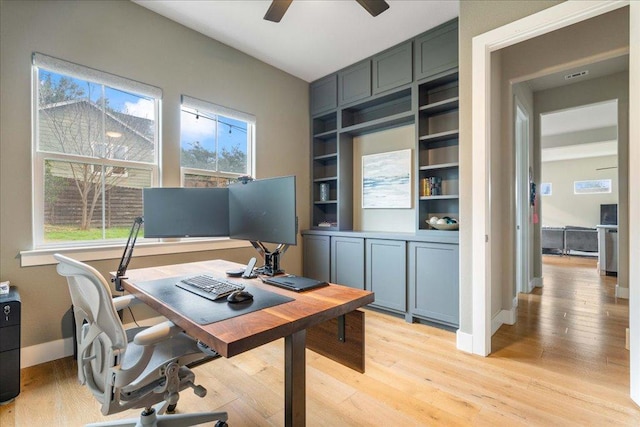 office space with light wood-style floors, a healthy amount of sunlight, and a ceiling fan