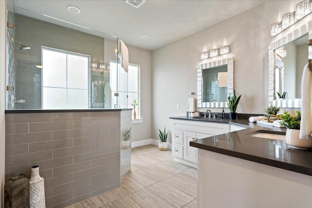 bathroom with visible vents, vanity, walk in shower, baseboards, and tile patterned floors