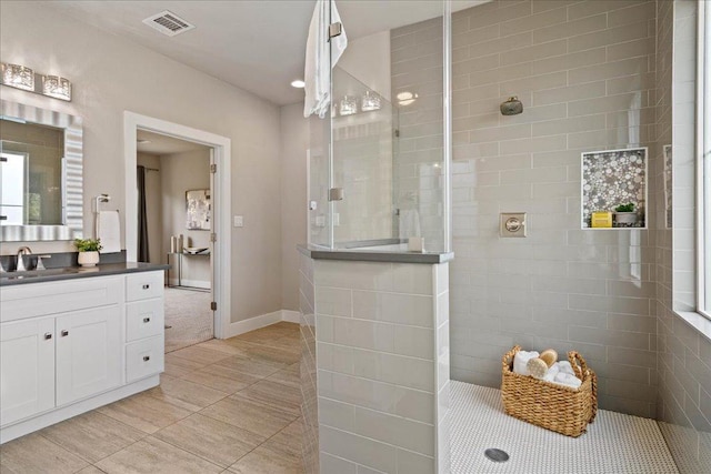 bathroom featuring visible vents, vanity, baseboards, and walk in shower