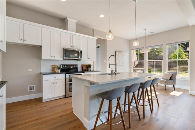 3011 Chisholm Trl, Austin, TX 78734 - kitchen featuring appliances with stainless steel finishes, light wood-style floors, white cabinets, tasteful backsplash, and an island with sink
