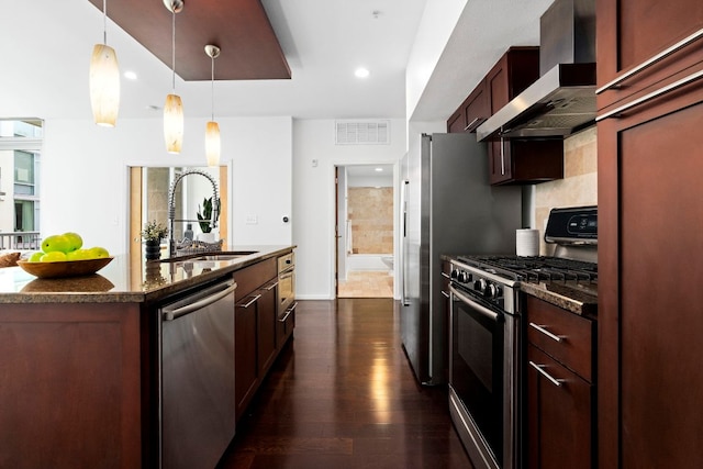 kitchen featuring stainless steel appliances, visible vents, dark wood-type flooring, a sink, and wall chimney range hood