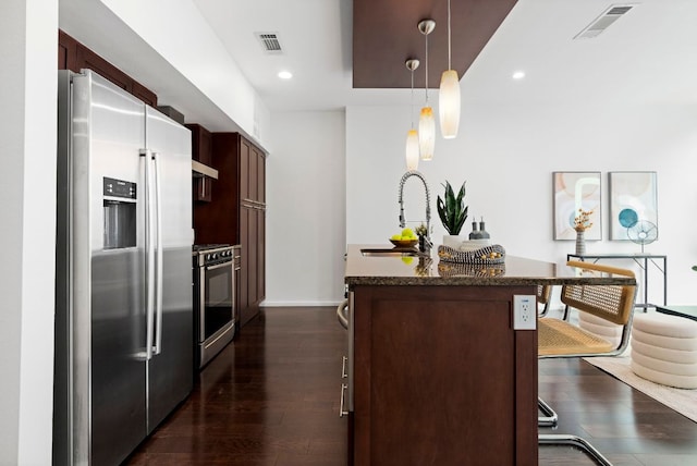 kitchen with visible vents, a center island with sink, a sink, dark wood finished floors, and appliances with stainless steel finishes