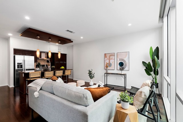 living area with baseboards, visible vents, dark wood-type flooring, and recessed lighting