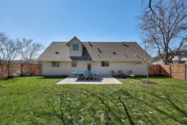 rear view of property with roof with shingles, a lawn, a patio area, and a fenced backyard