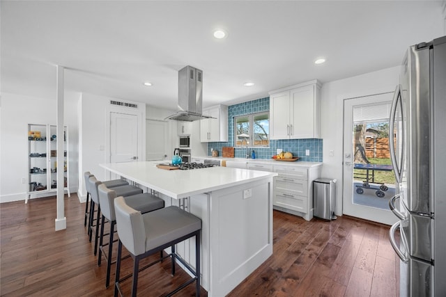 kitchen with freestanding refrigerator, white cabinets, a healthy amount of sunlight, and island exhaust hood