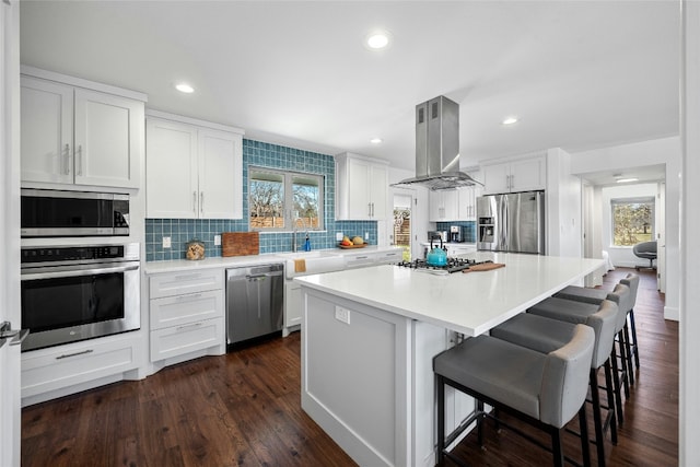 kitchen with appliances with stainless steel finishes, plenty of natural light, white cabinetry, and island range hood