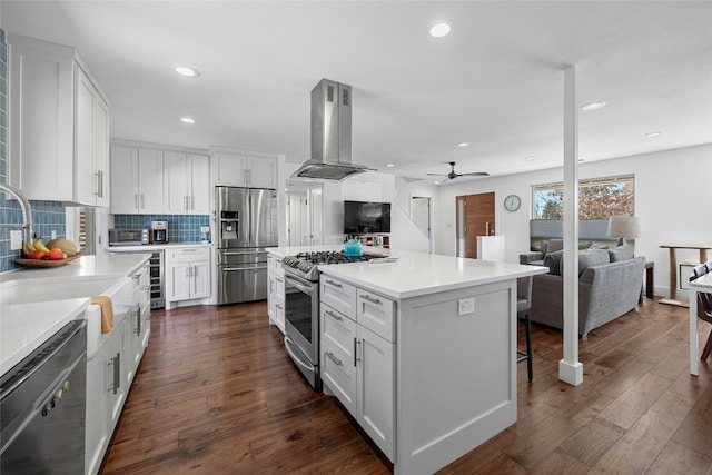 kitchen featuring stainless steel appliances, tasteful backsplash, island exhaust hood, and white cabinets