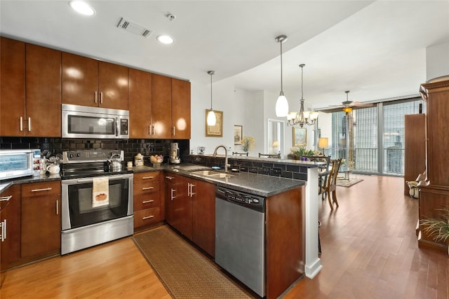 kitchen featuring visible vents, a peninsula, stainless steel appliances, floor to ceiling windows, and a sink