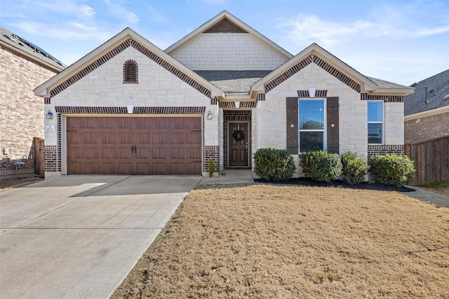 french country style house with a garage, brick siding, fence, driveway, and stone siding