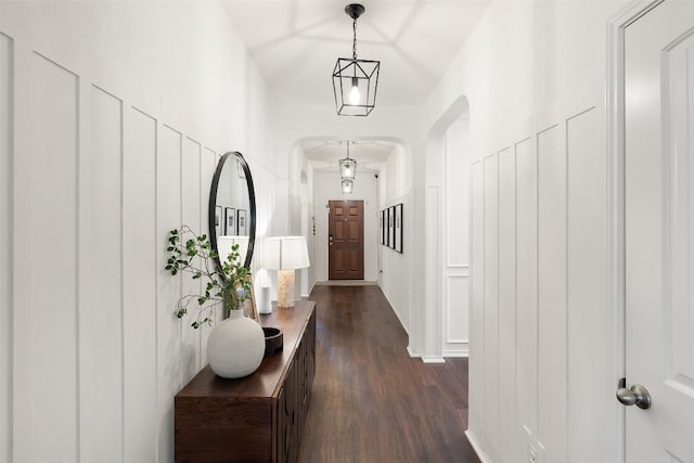 hall with arched walkways and dark wood-style flooring