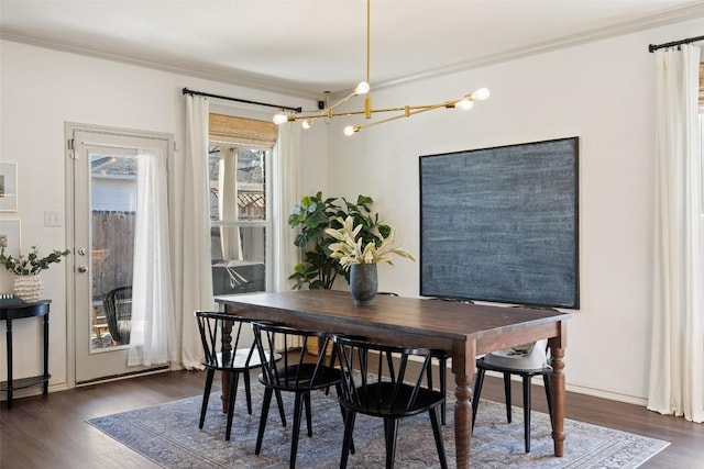 dining area with dark wood-style floors, a notable chandelier, and crown molding