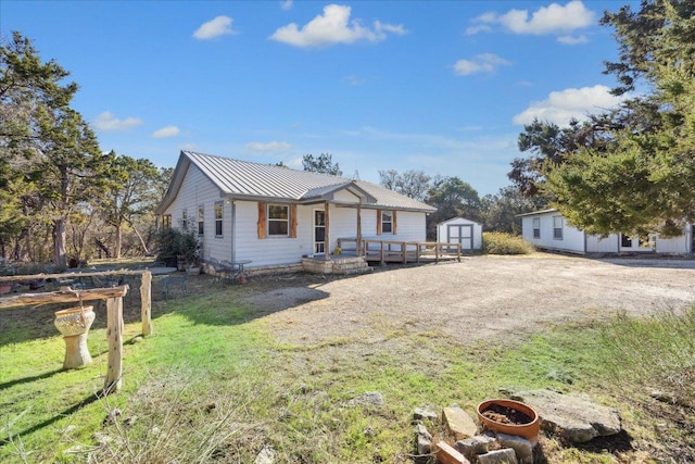 view of front of house with an outbuilding, metal roof, a front lawn, a storage unit, and a standing seam roof