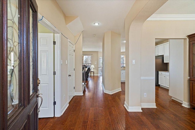 foyer with dark wood-type flooring, arched walkways, baseboards, and recessed lighting