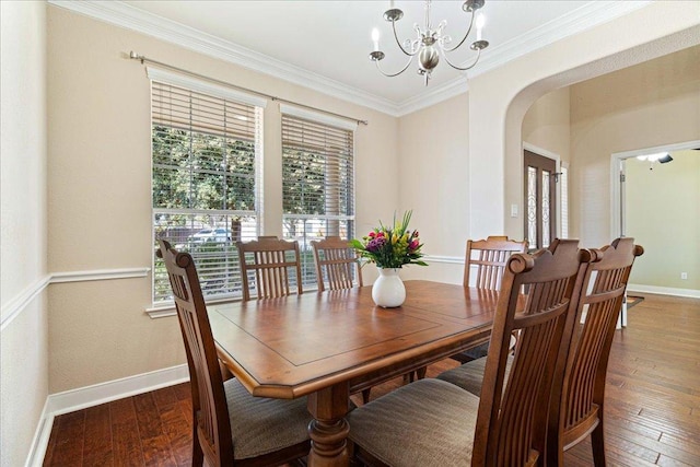 dining room with arched walkways, a notable chandelier, wood-type flooring, ornamental molding, and baseboards