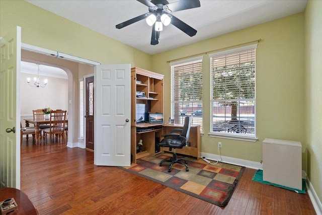 office area featuring ceiling fan with notable chandelier, arched walkways, baseboards, and hardwood / wood-style flooring