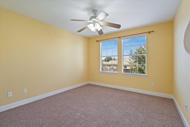 carpeted empty room featuring ceiling fan and baseboards