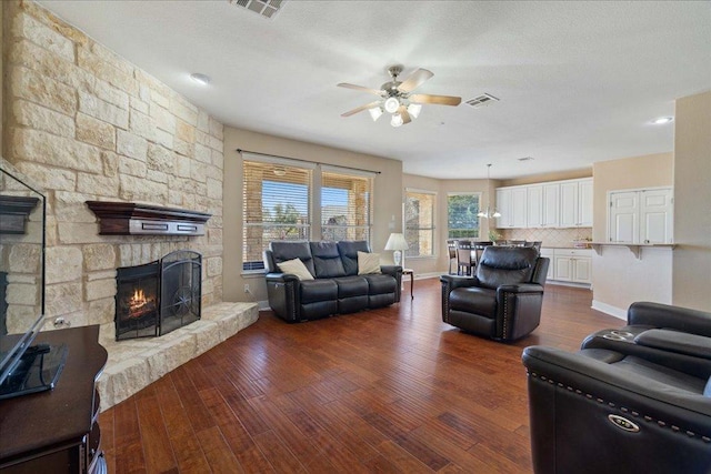 living area featuring dark wood-style flooring, visible vents, a fireplace, and ceiling fan