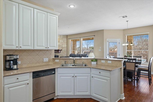 kitchen with visible vents, decorative backsplash, a peninsula, stainless steel dishwasher, and a sink