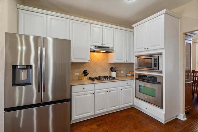 kitchen featuring white cabinets, dark wood finished floors, appliances with stainless steel finishes, under cabinet range hood, and backsplash