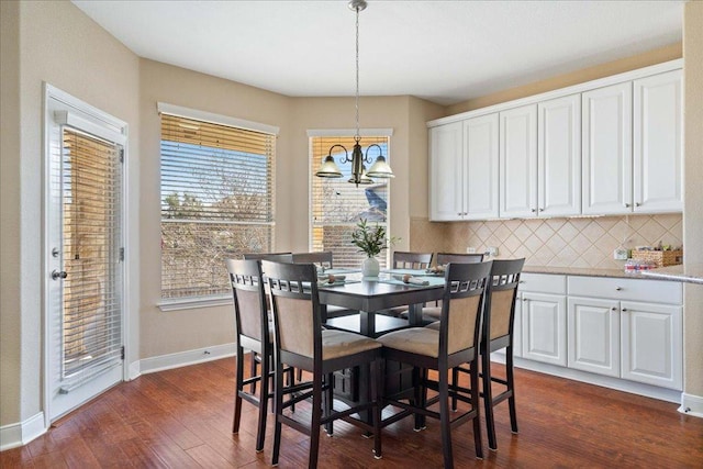 dining area featuring dark wood-style floors, baseboards, and an inviting chandelier