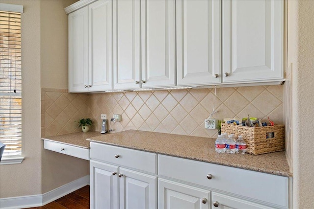 kitchen featuring tasteful backsplash, baseboards, white cabinets, dark wood-style flooring, and light stone countertops