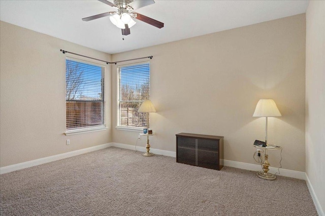 carpeted spare room featuring a ceiling fan and baseboards