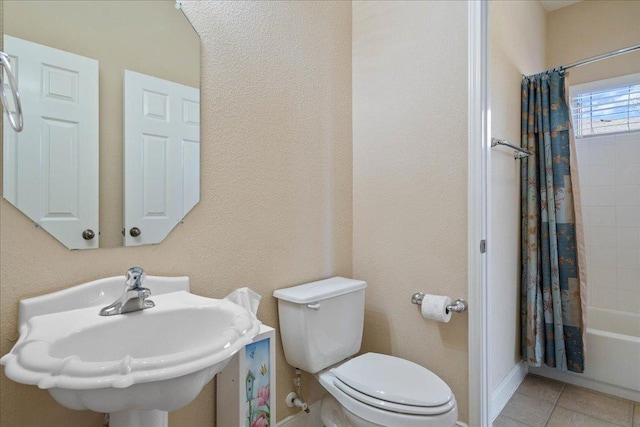 bathroom featuring shower / tub combo with curtain, a sink, toilet, and tile patterned floors