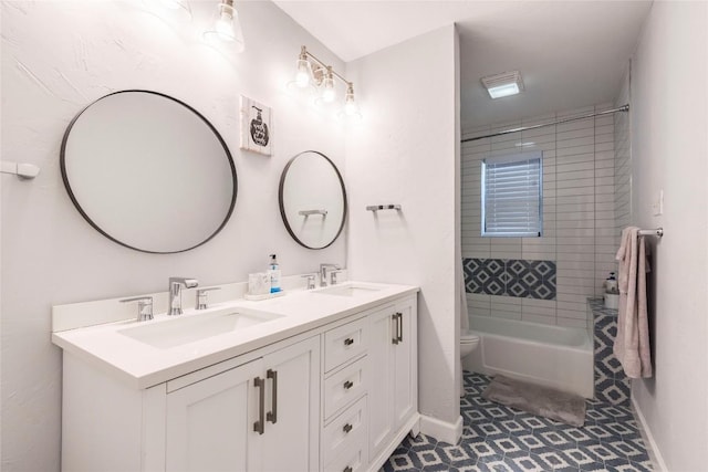 full bath featuring toilet, double vanity, baseboards, and a sink