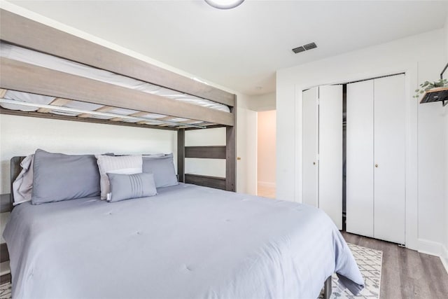 bedroom with a closet, wood finished floors, and visible vents