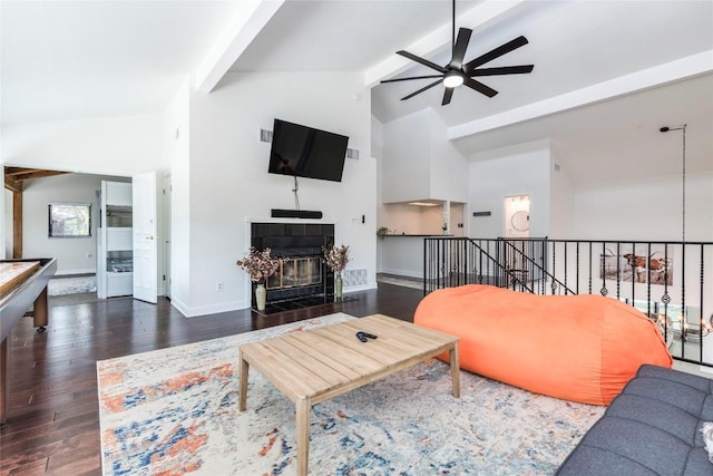 living room featuring baseboards, a tiled fireplace, a ceiling fan, wood finished floors, and beam ceiling