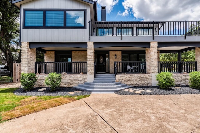 view of front of house featuring covered porch, brick siding, and a balcony