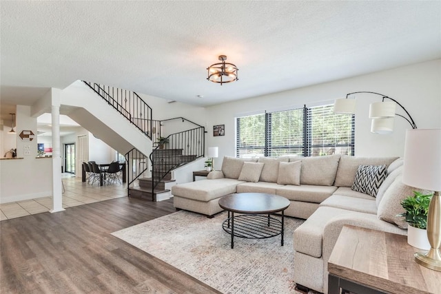 living area featuring stairs, a textured ceiling, wood finished floors, and ornate columns