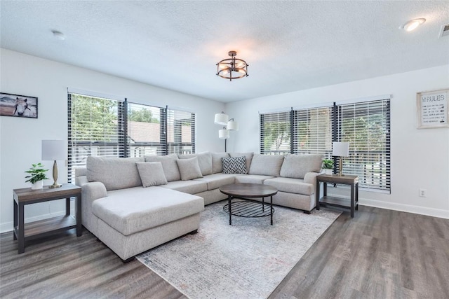 living room featuring visible vents, a textured ceiling, baseboards, and wood finished floors