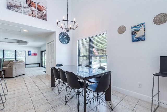 dining space featuring light tile patterned flooring, a towering ceiling, an inviting chandelier, and baseboards